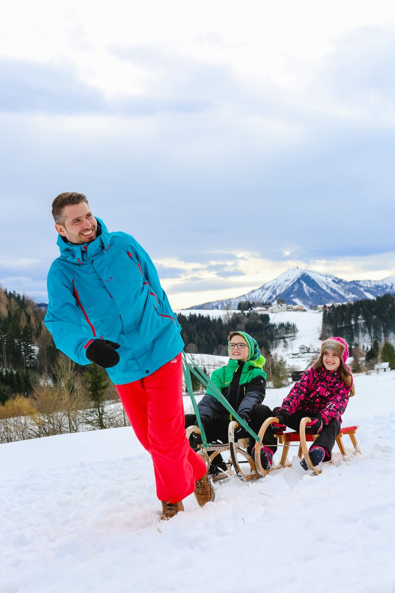 Mann zieht Schlitten mit Kindern drauf | © Niederösterreich Werbung / schwarz-koenig.at