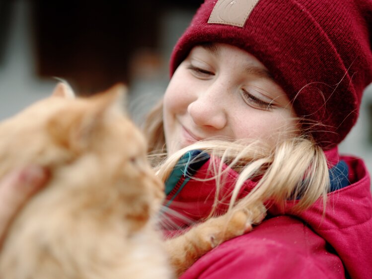 Kind kuschelt mit einer orangen Katze am Bauernhof | © Urlaub am Bauernhof Oberösterreich / Daniel Gollner