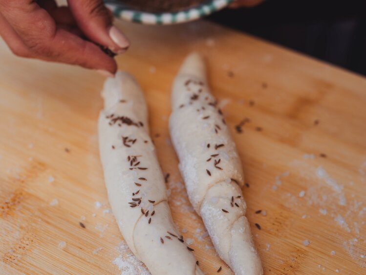 Salzstangerl mit Salz und Kümmel bestreuen | © Footprints Fotografie // cookingCatrin