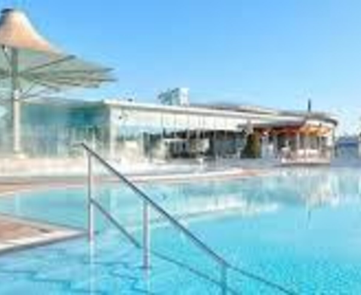 Der Außenpoolbereich des Bauernhofs mit dampfendem Wasser und modernen Gebäudeelementen.