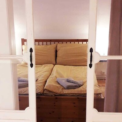 Schlafzimmer in der Unterkunft mit Doppelbett, Holzrahmen und karierter Bettwäsche.