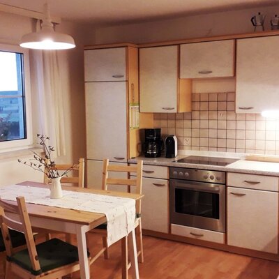 Küche des Ferienhauses mit Esstisch, Herd, Backofen, Kühlschrank und Mikrowelle.