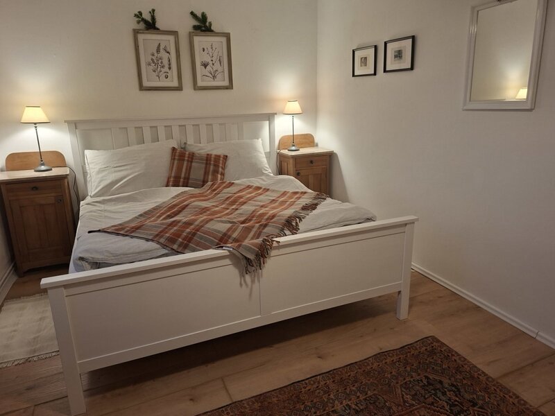 Das Schlafzimmer des Ferienhauses mit Kingsize Bett und Aussicht in den Garten.