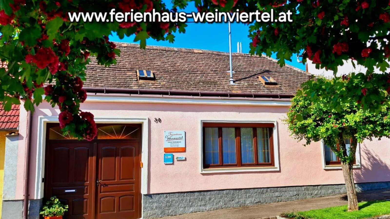 Das Ferienhaus mit heller Fassade, braunen Fenstern und Türen sowie begrünten Bereichen davor.