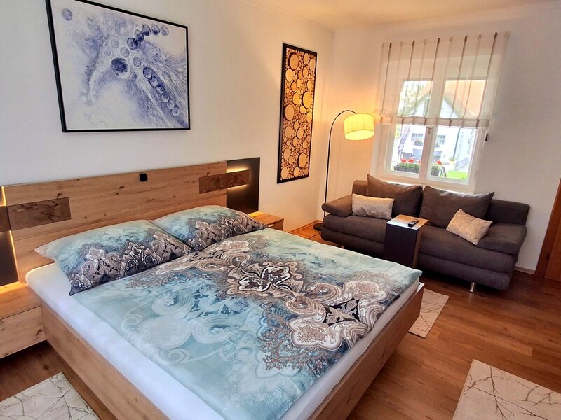 Schlafzimmer im Bauernhof mit Doppelbett, integrierter Beleuchtung, Nachttischen und Sofa.