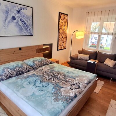 Schlafzimmer im Bauernhof mit Doppelbett, integrierter Beleuchtung, Nachttischen und Sofa.