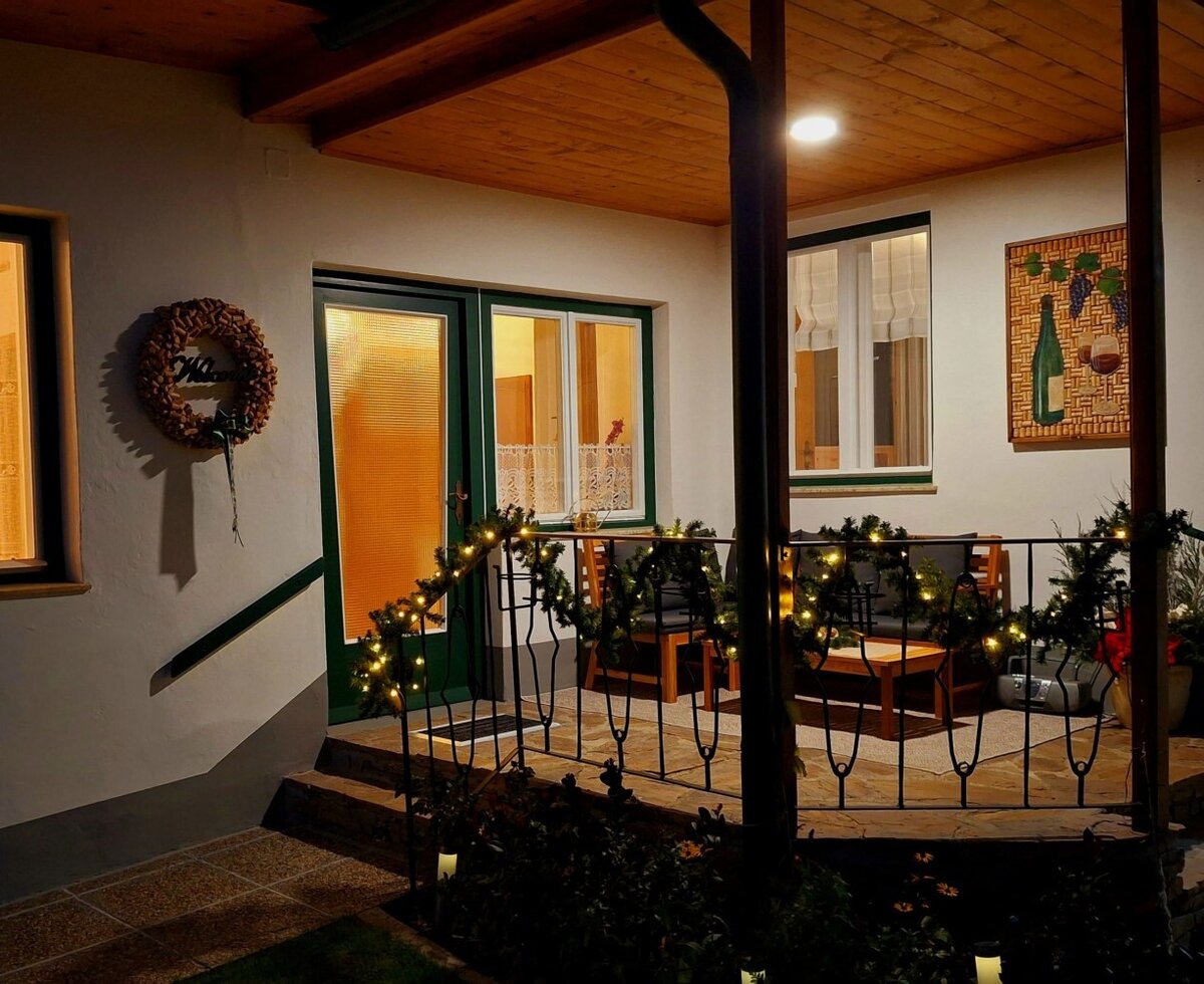 Die überdachte Terrasse des Bauernhofs mit Sitzgelegenheiten, einem Tisch und Außenbeleuchtung.