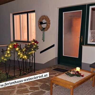 Die festlich beleuchtete Terrasse des Bauernhofs mit Sitzmöbeln und Eingangsbereich.