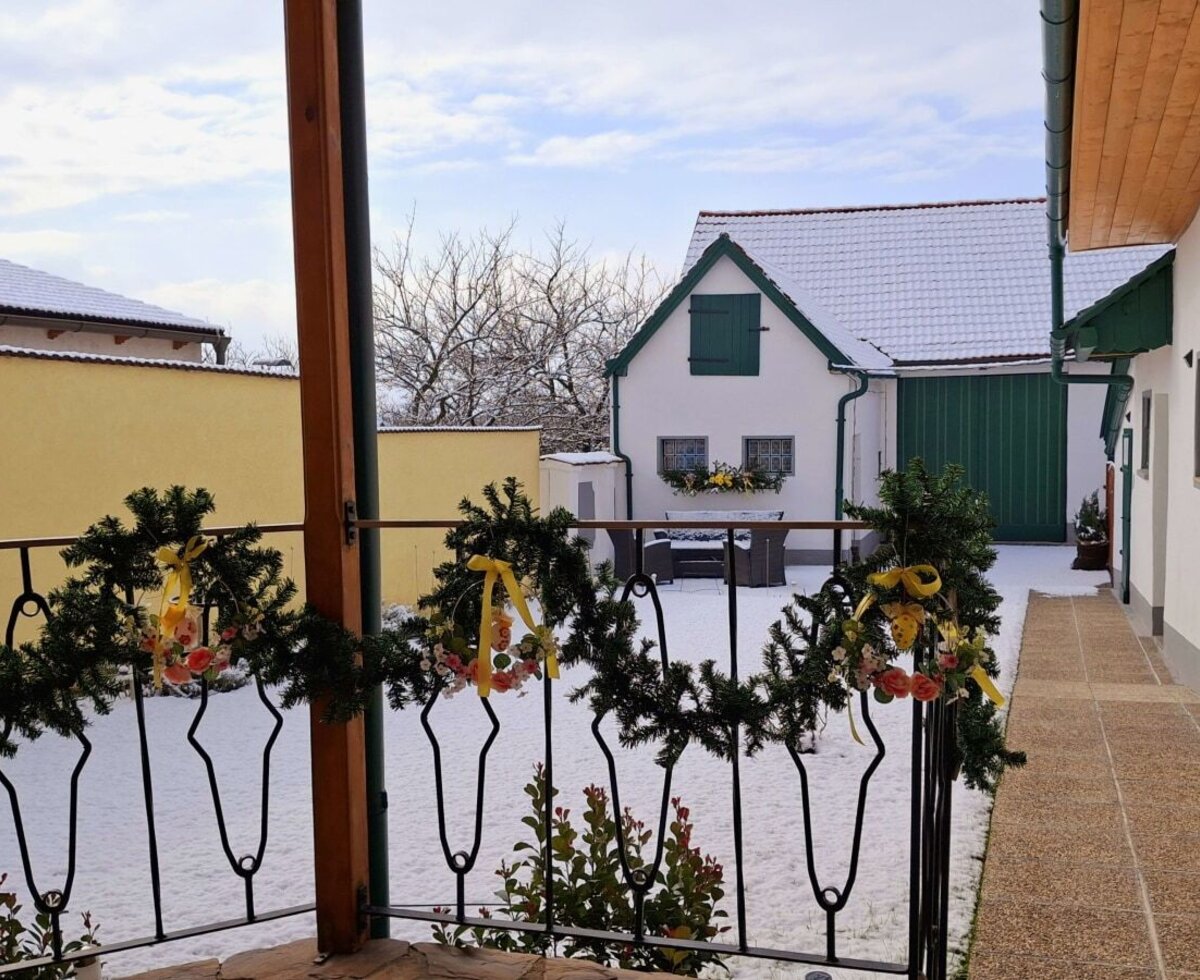 Der schneebedeckte Innenhof des Bauernhofs, gesehen von einem Balkon mit festlicher Dekoration.