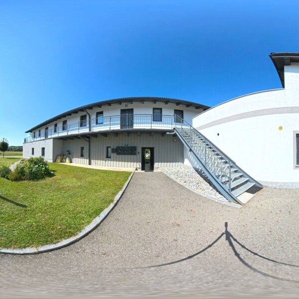 Der einladende Außenbereich des Hauses mit einem gepflegten Rasen und modernen Gebäuden unter strahlend blauem Himmel.