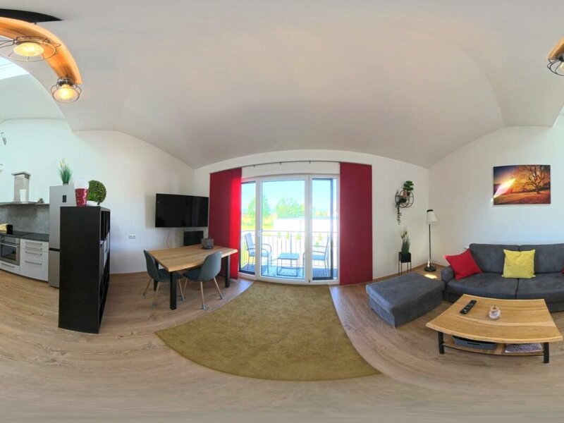 Der lichtdurchflutete Wohnbereich des Hauses bietet eine moderne Küchenzeile, eine gemütliche Sofaecke und Zugang zum Balkon.
