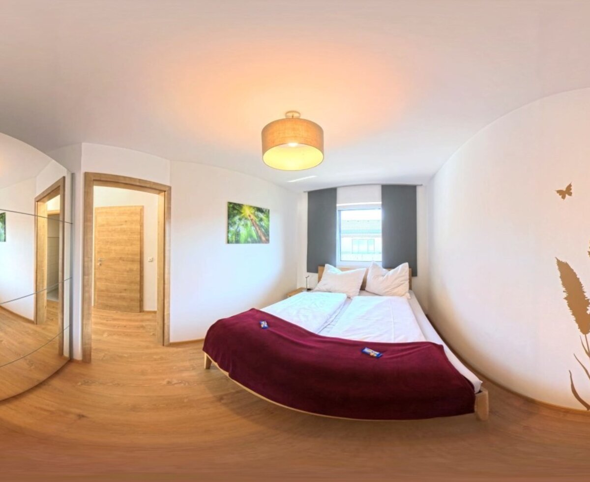 Ein gemütliches Schlafzimmer des Hauses mit einem einladenden Doppelbett, warmen Holzelementen und einer dekorativen Wandgestaltung.
