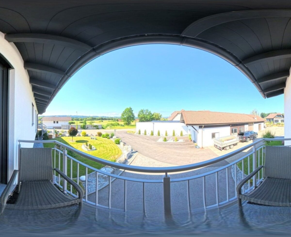 Einladender Balkon des Hauses mit gemütlichen Sitzmöbeln und weitem Blick auf den sonnigen Innenhof.