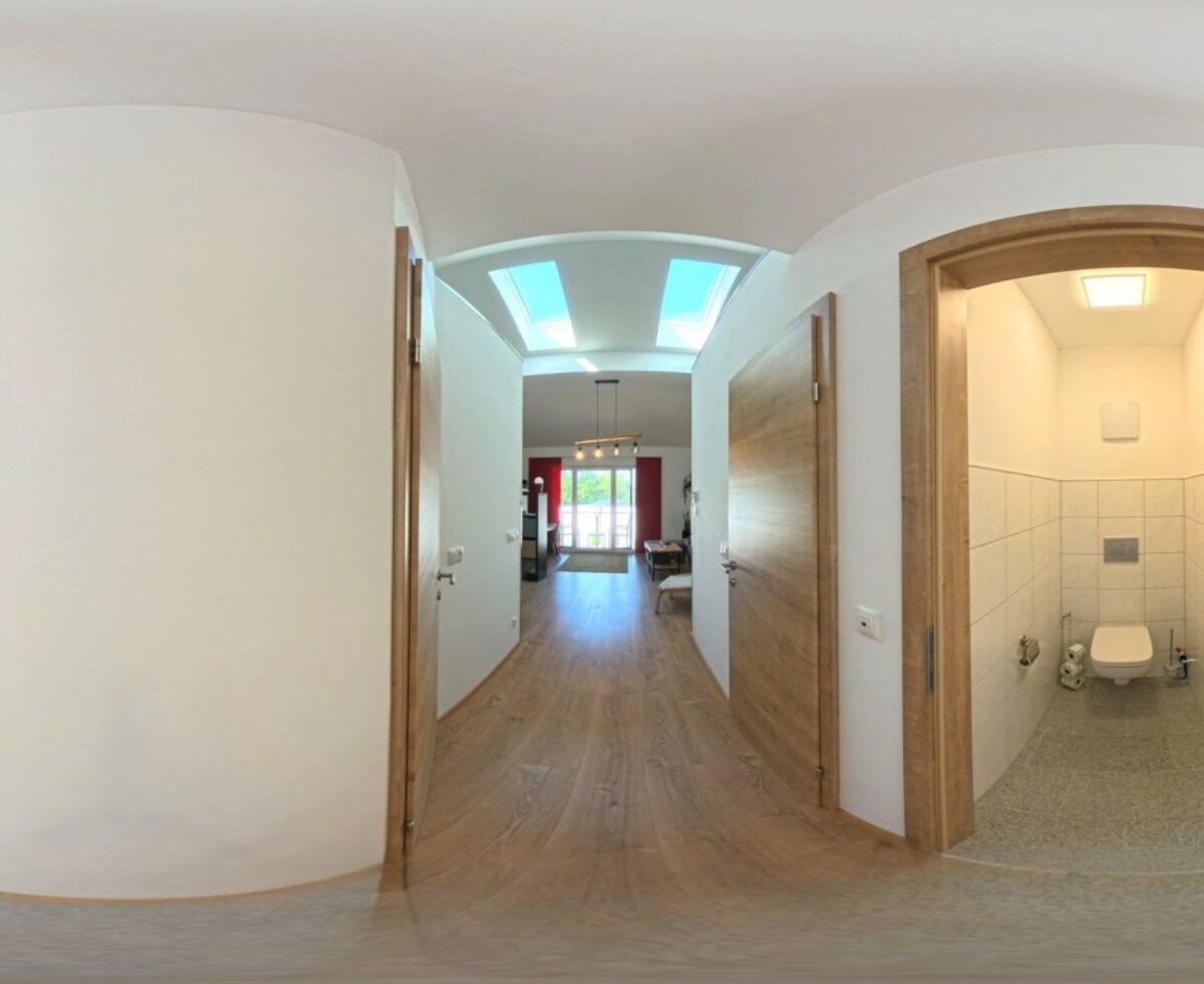 Ein heller, einladender Flur des Hauses mit modernen Holztüren, Holzboden und einem separaten, gefliesten WC.