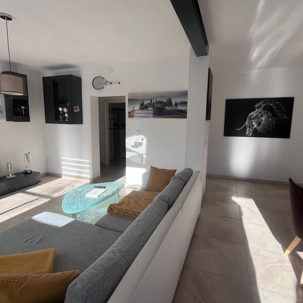 Der Wohnbereich verfügt über ein Sofa, einen Fernseher und einen Couchtisch aus Glas, mit einem Essbereich auf der Seite.