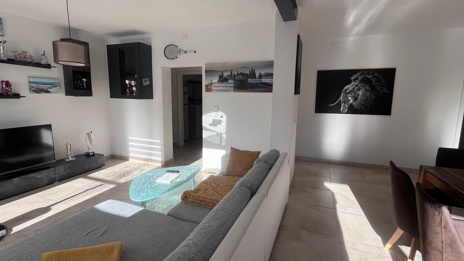 Der Wohnbereich verfügt über ein Sofa, einen Fernseher und einen Couchtisch aus Glas, mit einem Essbereich auf der Seite.