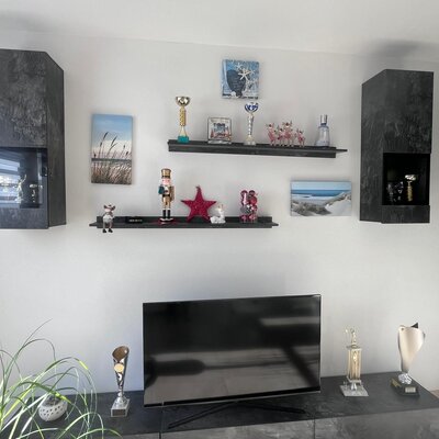 Wohnbereich mit Fernseher und dekorativen Wandregalen.