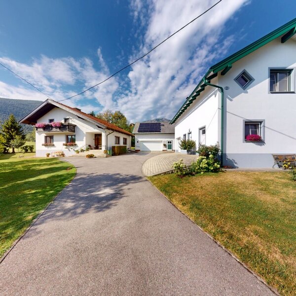 Der einladende Außenbereich des Bauernhofs mit gepflegten Grünflächen und traditionellen Gebäuden unter blauem Himmel.
