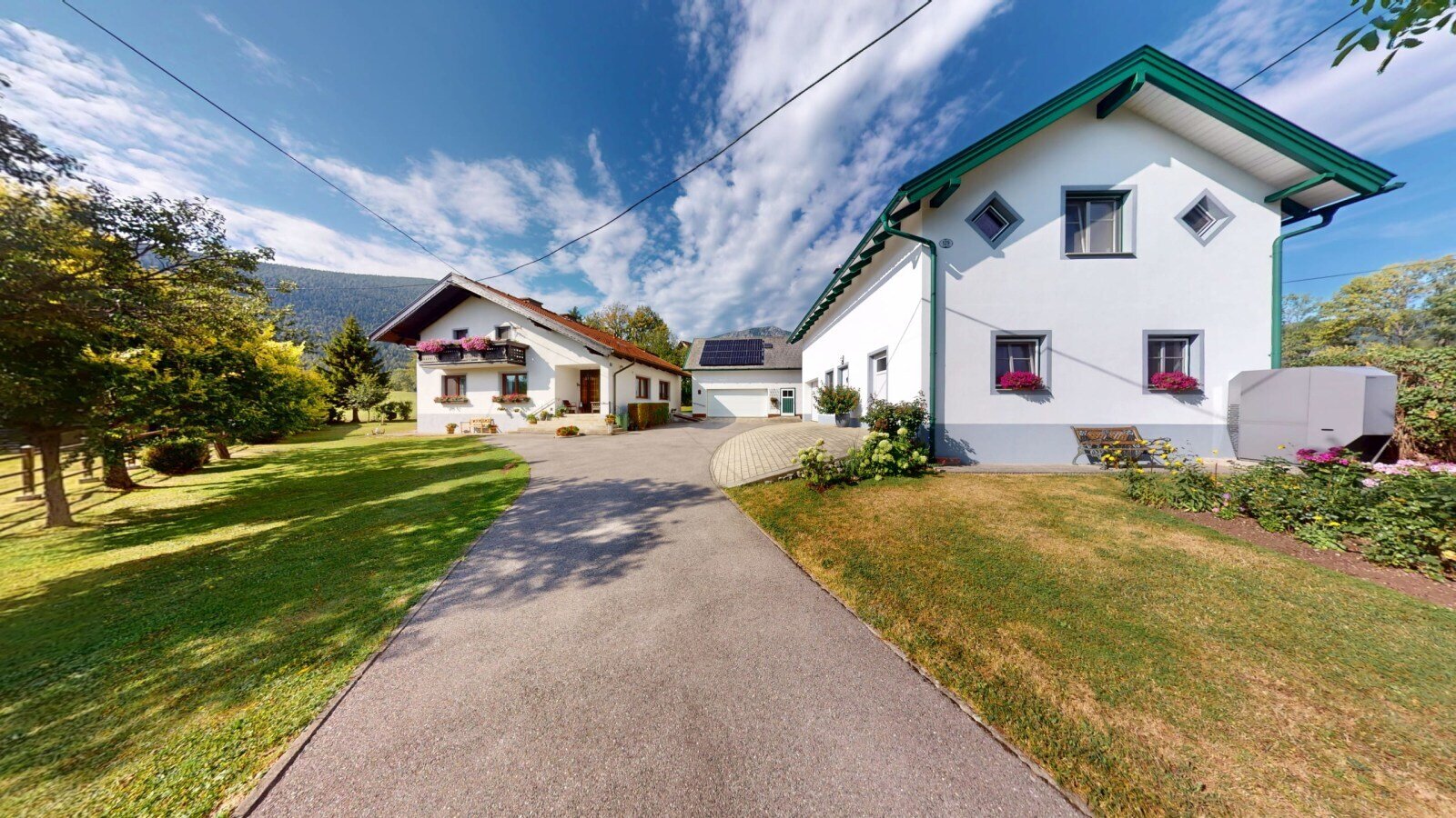 Der einladende Außenbereich des Bauernhofs mit gepflegten Grünflächen und traditionellen Gebäuden unter blauem Himmel.