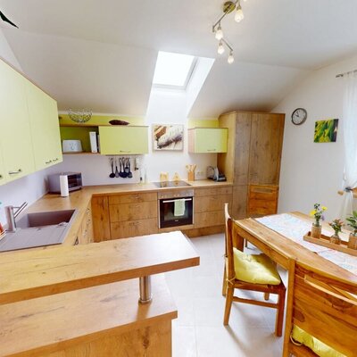 Die helle und freundliche Küche der Ferienwohnung überzeugt mit einem gemütlichen Essbereich aus Holz und moderner Ausstattung.