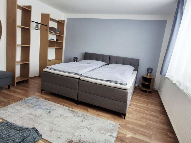 Ein einladendes Schlafzimmer im Haus mit einem komfortablen Doppelbett, stilvollen Holzregalen und wohnlichen Holzböden.
