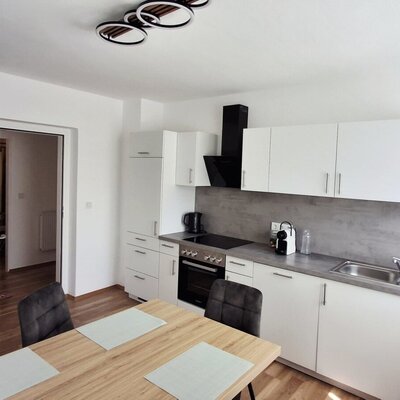 Die moderne und helle Küche des Hauses bietet eine hochwertige Ausstattung und einen einladenden Essbereich aus Holz.