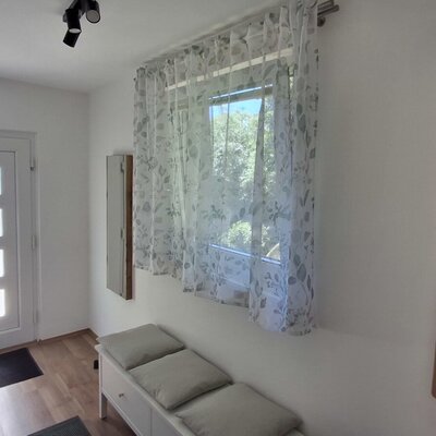 Der helle Eingangsbereich des Hauses mit einer einladenden Sitzbank und einer modernen Holzgarderobe.
