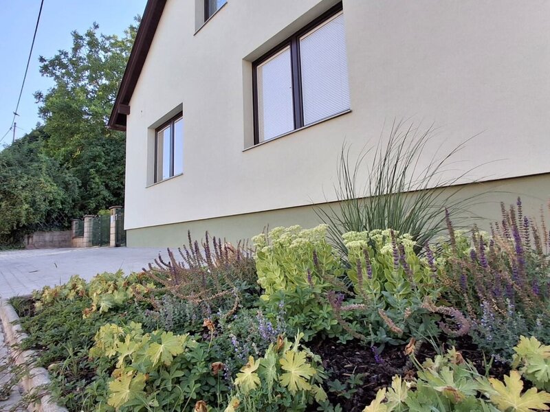 Die einladende Außenansicht des Gästehauses mit einem liebevoll angelegten, bunt bepflanzten Blumenbeet im Vordergrund.