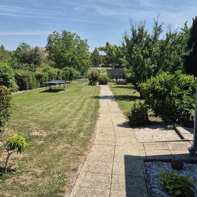 Der einladende Garten des Bauernhofs mit einer weitläufigen Rasenfläche, einer Tischtennisplatte und einem gepflegten Steinweg.