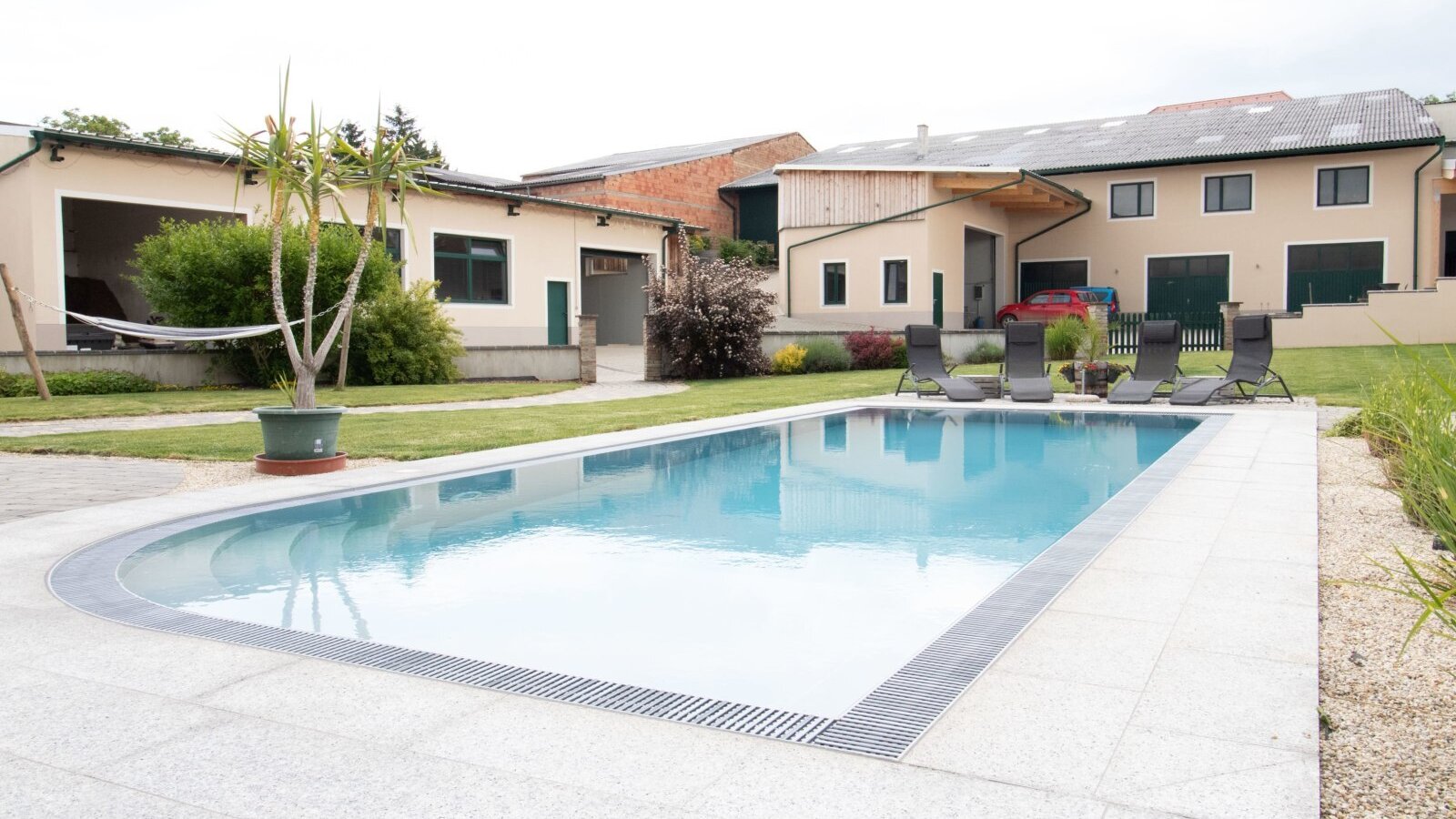 Der Außenpool mit Sonnenliegen im Garten