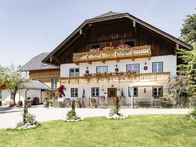 Außenansicht des Appartementsgebäudes mit traditioneller Architektur, Holzbalkonen und Blumenkästen. | © Urlaub am Bauernhof Oberösterreich / Bettina Gangl